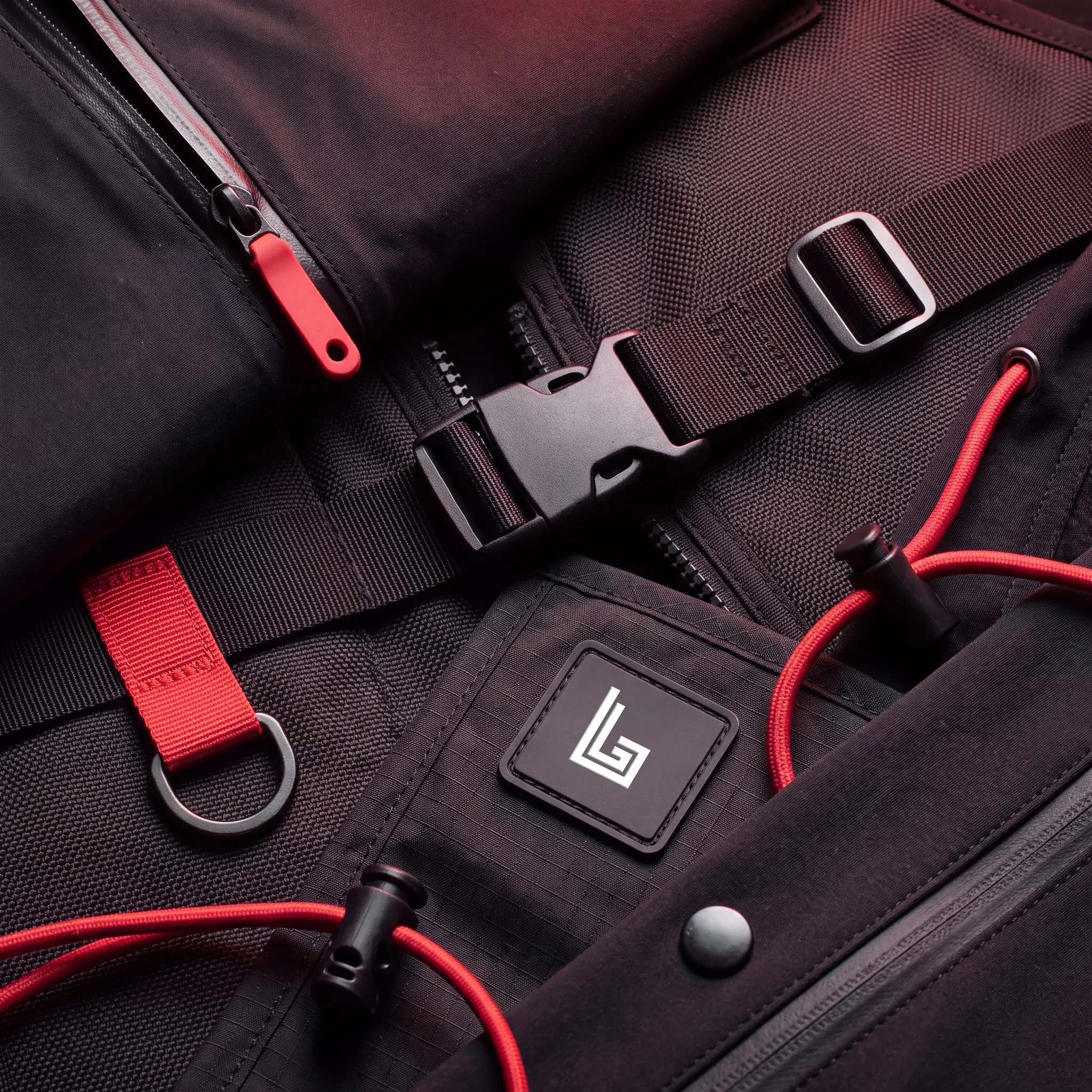 Close-up of branded zip pulls, rubber patch, buckles and zip pockets on custom techwear made by Lethletic